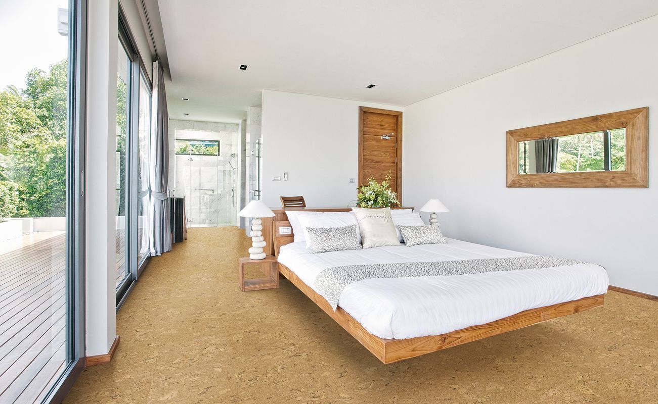 Helles Schlafzimmer mit einem schwebenden Bett, Holzfußboden und großen Fenstern, die auf eine Terrasse blicken.